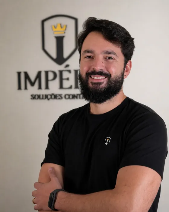 André, sócio da Império, de braços cruzados em frente ao logo no escritório