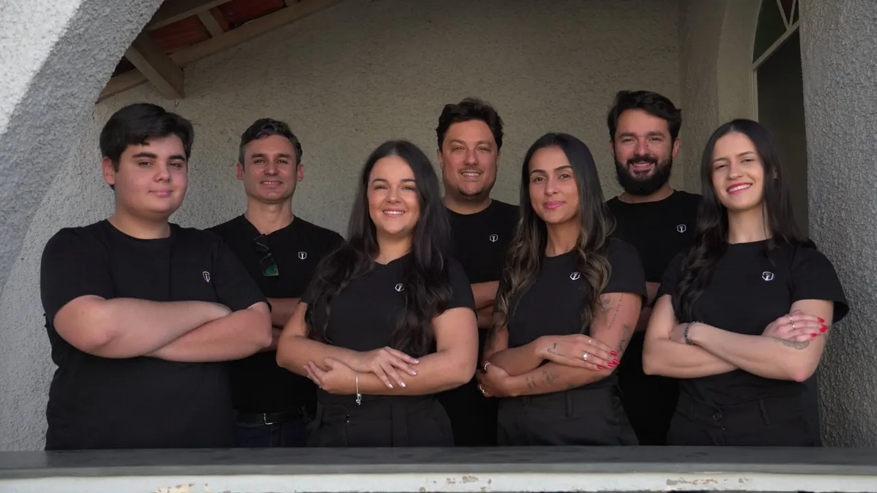 Equipe da Império com camisetas pretas da marca, de braços cruzados na varanda do escritório
