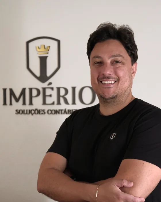 Lucas, sócio da Império, sorrindo em frente ao logo no escritório